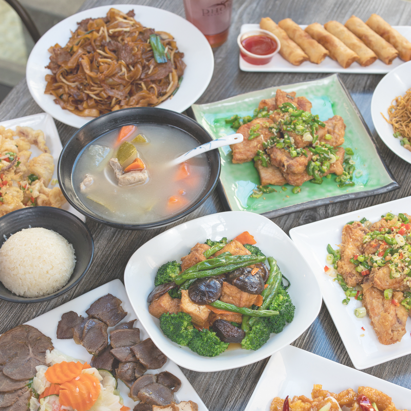 An assortment of Phoenix dishes including noodles, veggie dishes, chicken entrees, and fried appetizers. 